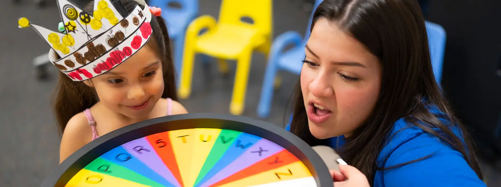 Educator with student spinning colorful wheel.