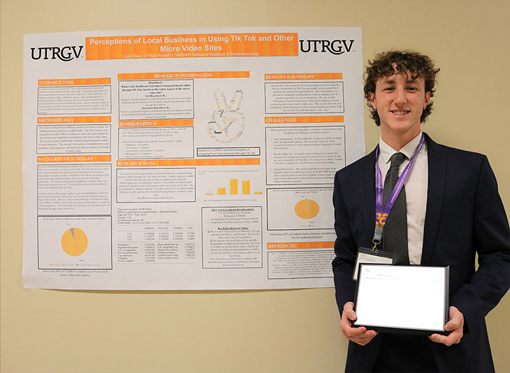 Student Colin Baus holding presentation poster. 