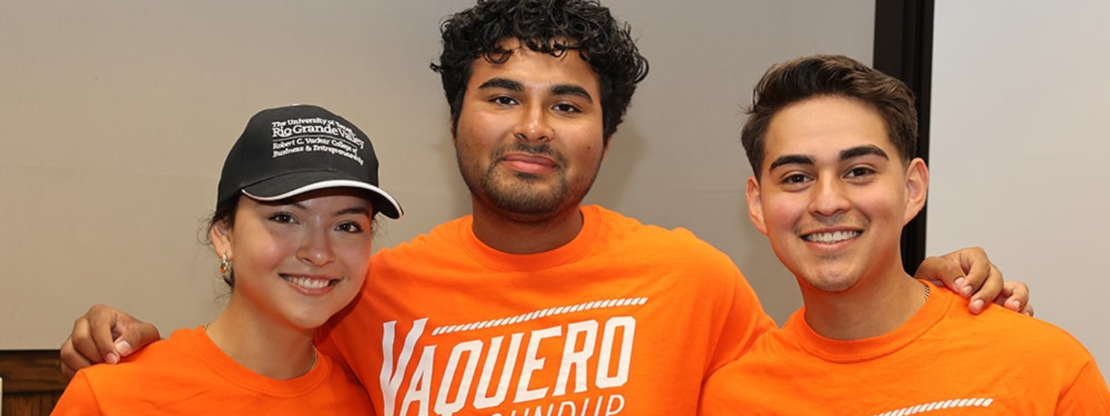 Three students, sporting Vaquero shirts, happily pose for the camera.