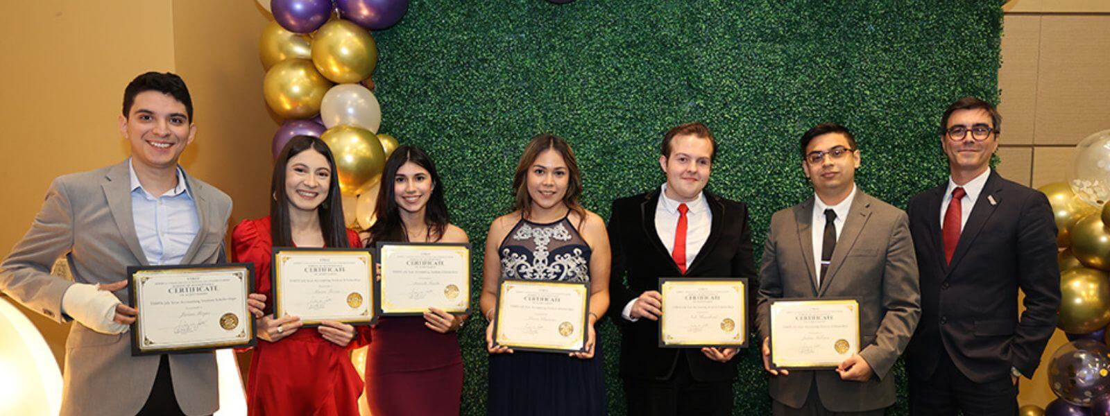 Students smile while holding certificates at School of Accountancy gala.